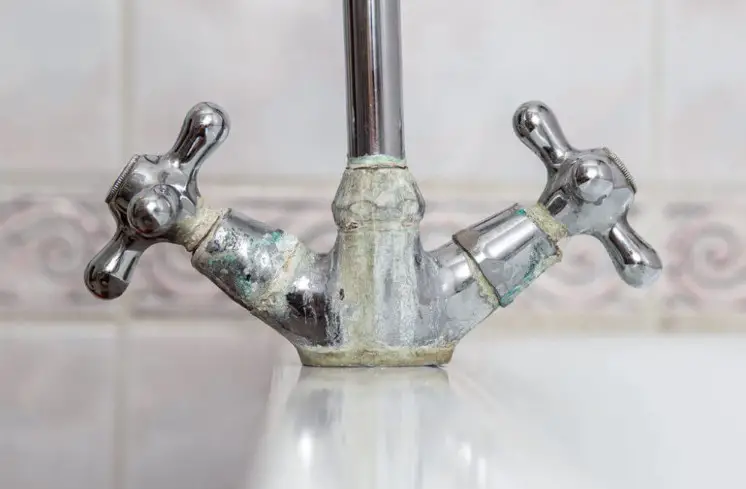 How do you prevent hard water buildup on bathroom faucets?